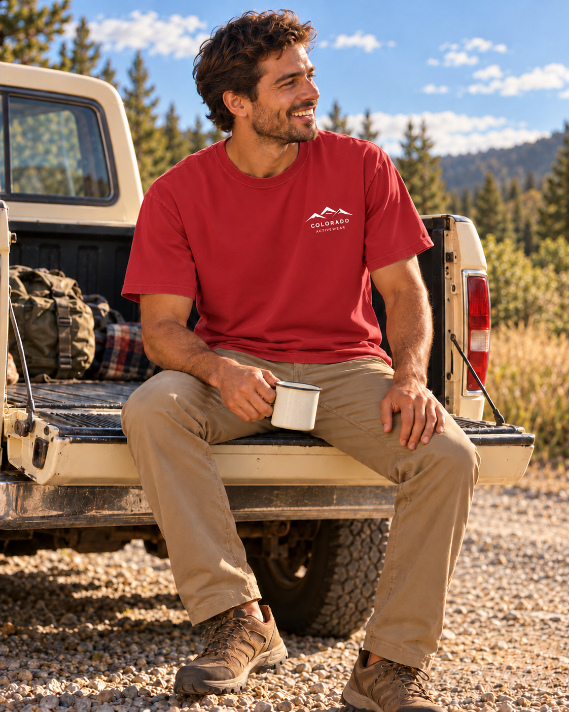 Man wearing a Crimson Alpine Social Club tee at a truck tailgate, showing the small Colorado Activewear chest logo.