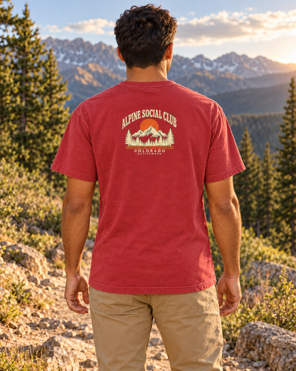 Man wearing the Alpine Social Club Heavyweight Tee in Crimson outdoors, showing the compact retro mountain back graphic.