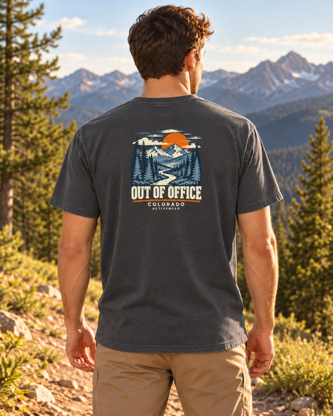 Man wearing the Out of Office Heavyweight Tee in Pepper outdoors, showing the compact retro mountain and sunset back graphic.